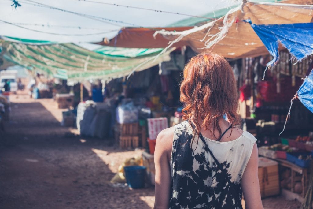 A young caucasian woman is walking around a small town in a developing country